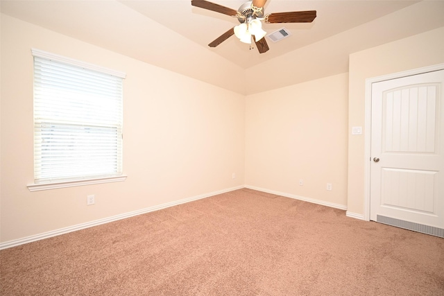 carpeted spare room featuring vaulted ceiling and ceiling fan