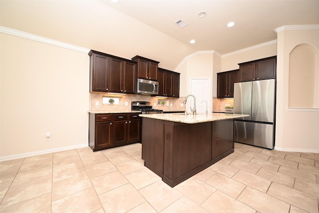 kitchen with a kitchen island with sink, vaulted ceiling, light stone countertops, appliances with stainless steel finishes, and light tile patterned flooring