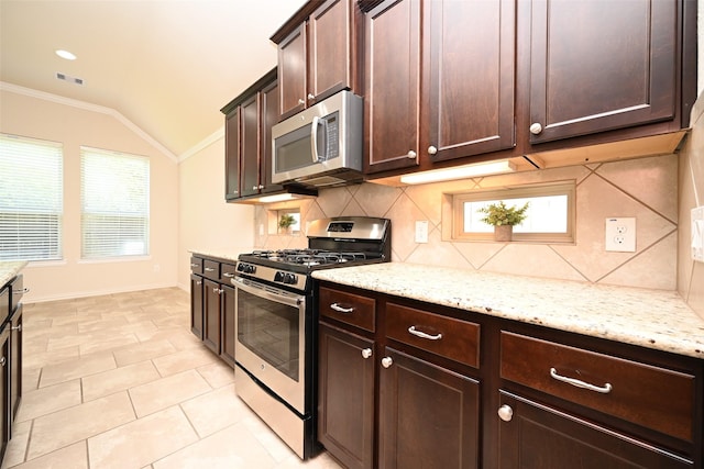 kitchen with light stone countertops, backsplash, stainless steel appliances, vaulted ceiling, and crown molding