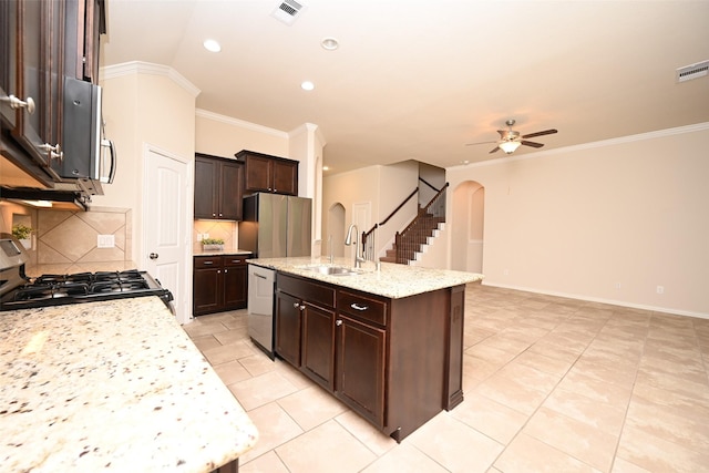 kitchen featuring decorative backsplash, light stone counters, stainless steel appliances, a kitchen island with sink, and ceiling fan