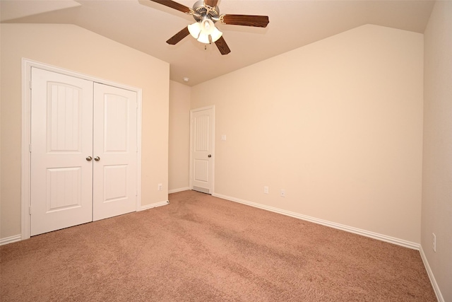 unfurnished bedroom featuring ceiling fan, a closet, light colored carpet, and vaulted ceiling