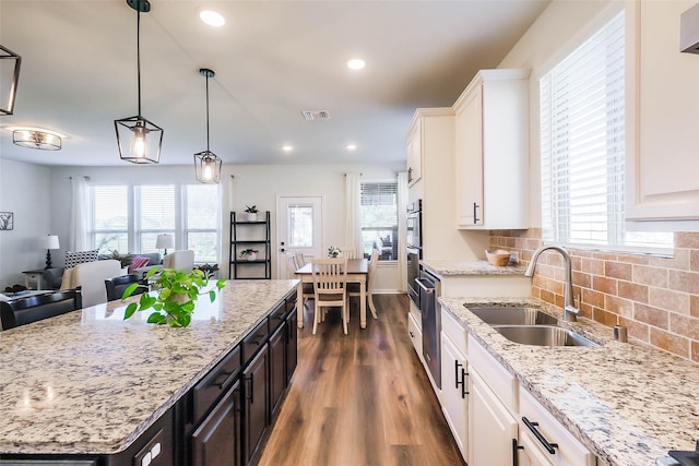 kitchen with dark hardwood / wood-style flooring, tasteful backsplash, light stone counters, sink, and white cabinetry