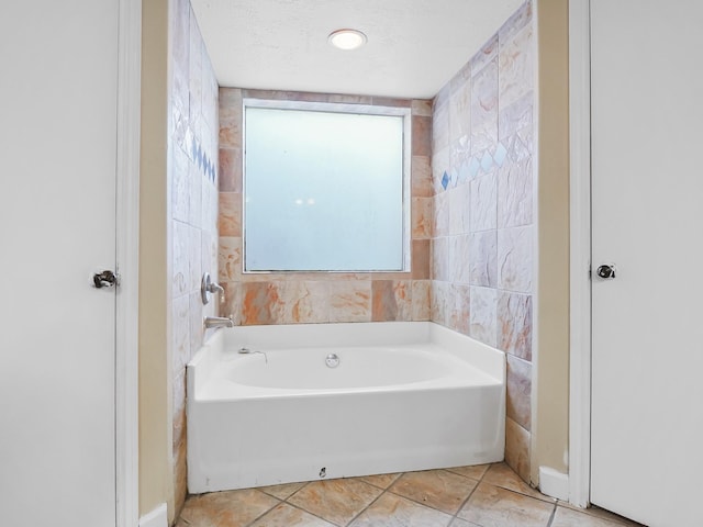 bathroom with a tub and a textured ceiling