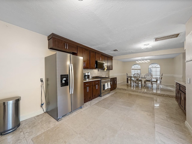 kitchen with appliances with stainless steel finishes, backsplash, a textured ceiling, and dark brown cabinets