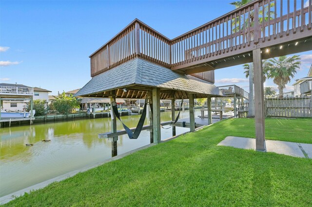 view of dock with a lawn and a water view