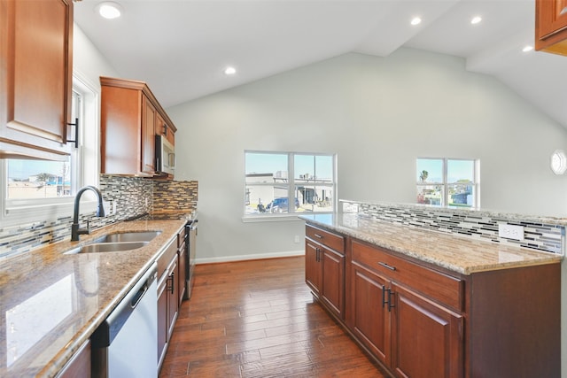 kitchen with sink, a center island, dark wood-type flooring, light stone counters, and appliances with stainless steel finishes