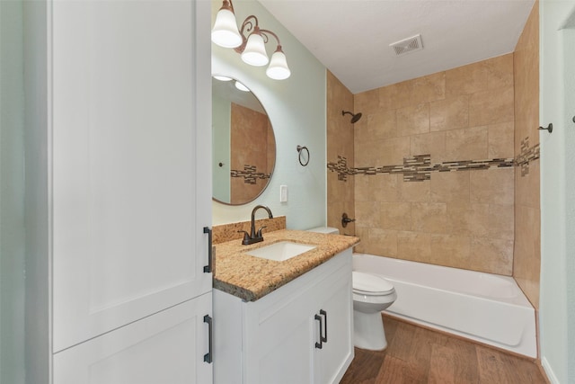 full bathroom with tiled shower / bath, vanity, wood-type flooring, and toilet