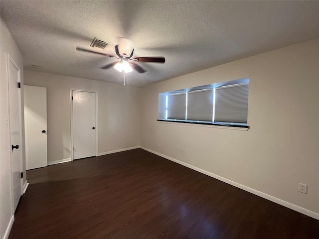 spare room with a textured ceiling, ceiling fan, and dark hardwood / wood-style floors