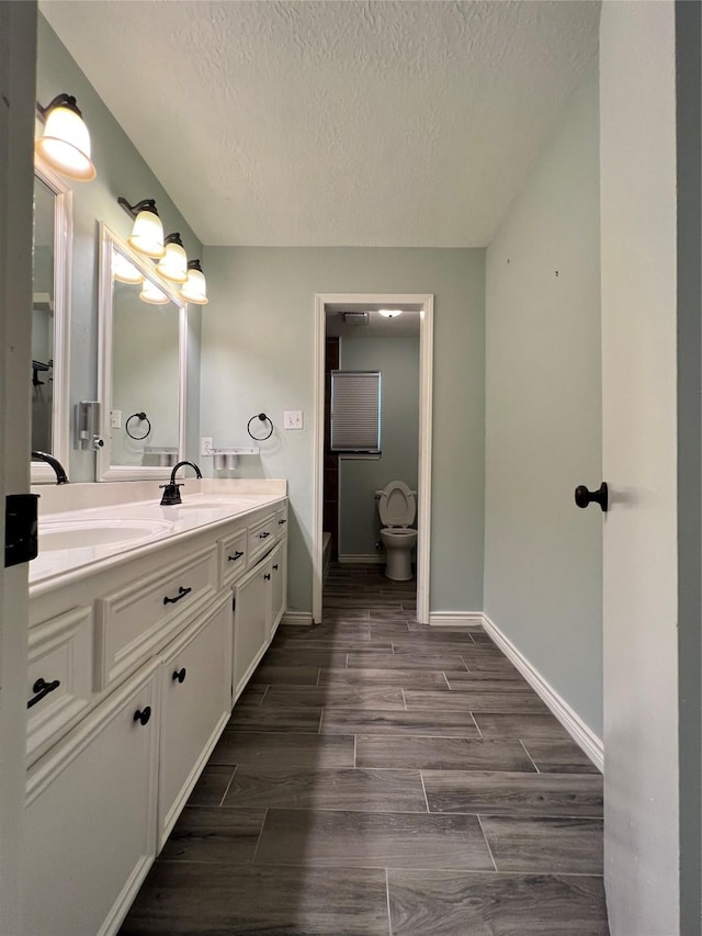 bathroom with a textured ceiling, vanity, and toilet