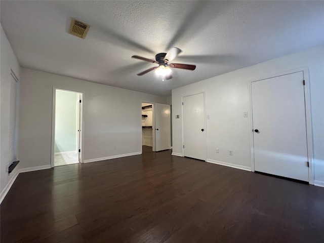 unfurnished bedroom with connected bathroom, ceiling fan, dark hardwood / wood-style floors, and a textured ceiling