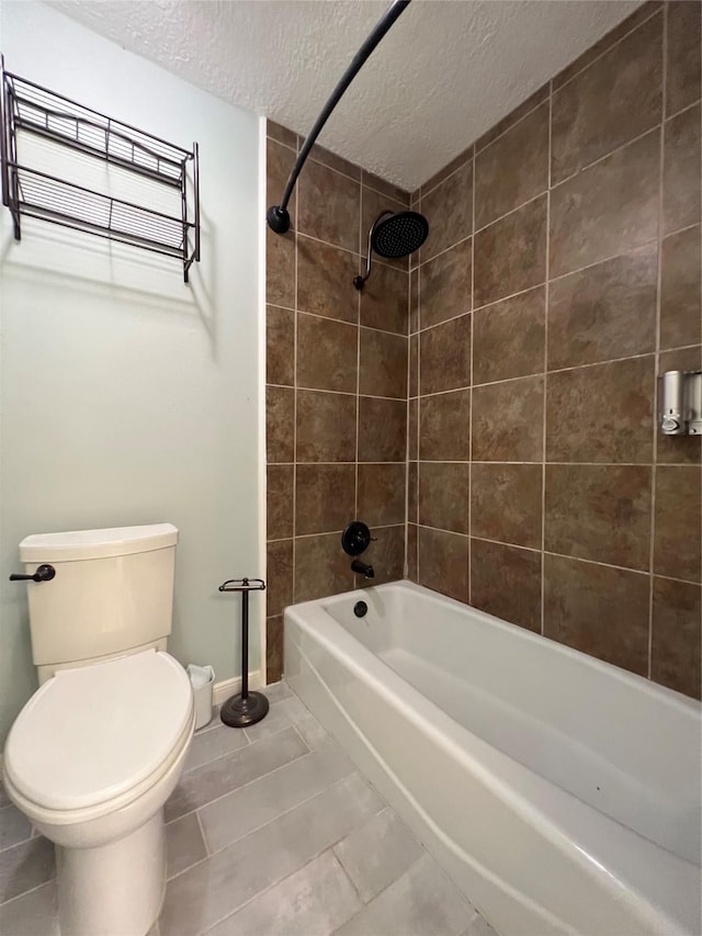 bathroom with tile patterned floors, toilet, a textured ceiling, and tiled shower / bath