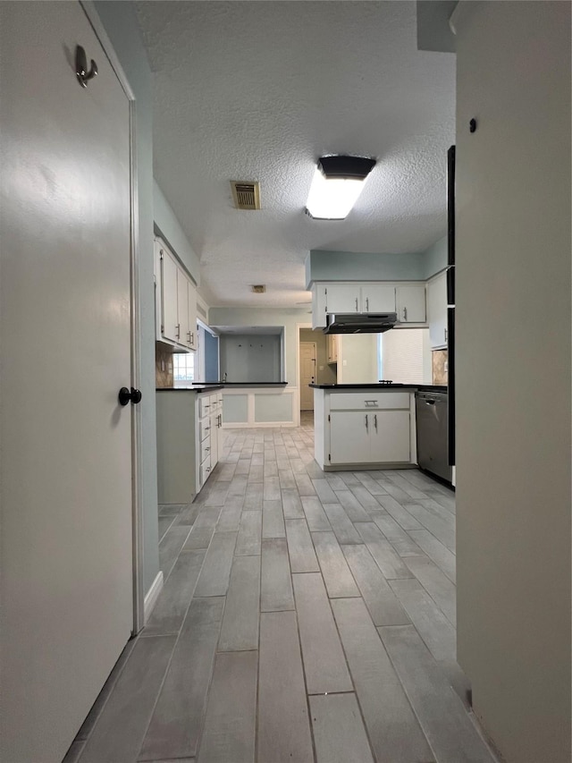 kitchen featuring dishwasher, a textured ceiling, and white cabinetry