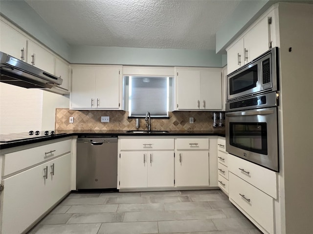 kitchen with tasteful backsplash, white cabinetry, stainless steel appliances, and a textured ceiling