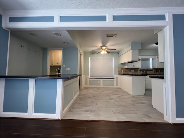 kitchen with white cabinets, sink, ceiling fan, tasteful backsplash, and kitchen peninsula