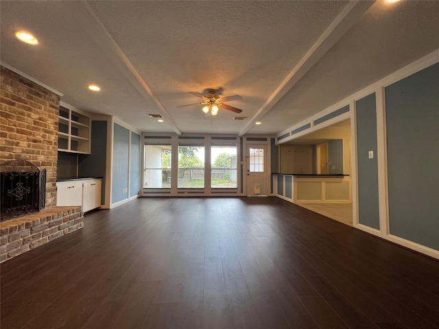 unfurnished living room with ceiling fan, a fireplace, dark wood-type flooring, and a textured ceiling