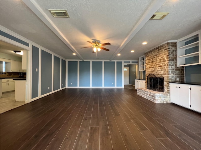 unfurnished living room featuring a textured ceiling, ceiling fan, a fireplace, and dark hardwood / wood-style floors