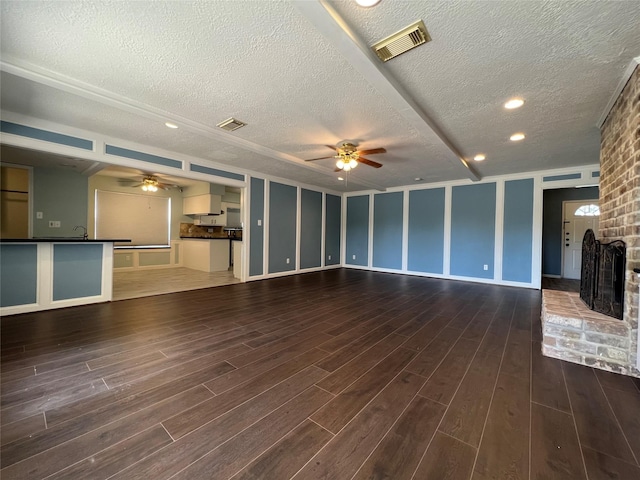 unfurnished living room featuring ceiling fan, a fireplace, and dark wood-type flooring