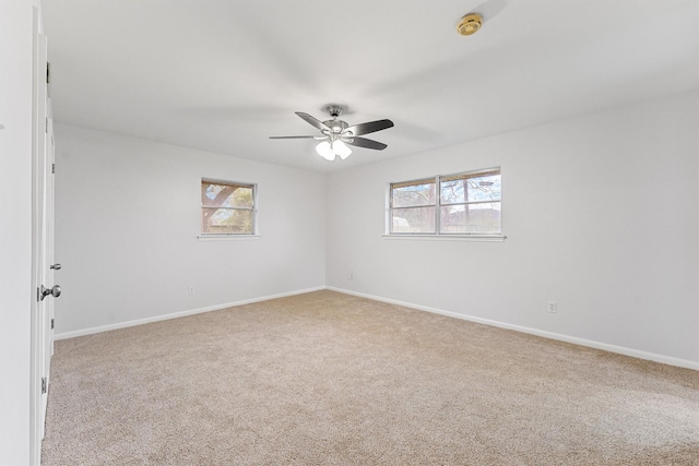 spare room featuring ceiling fan, light colored carpet, and a wealth of natural light