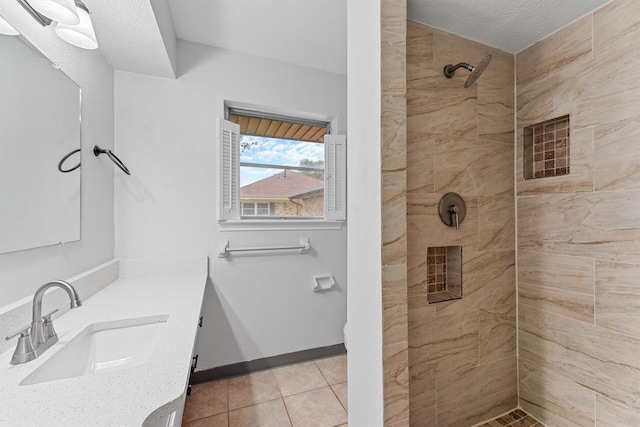 bathroom featuring tile patterned flooring, vanity, and a tile shower