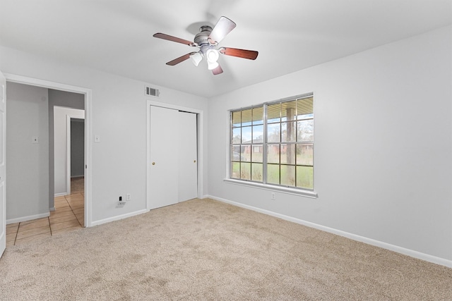 unfurnished bedroom with light carpet, a closet, and ceiling fan