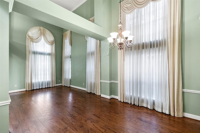 empty room featuring a notable chandelier and dark wood-type flooring