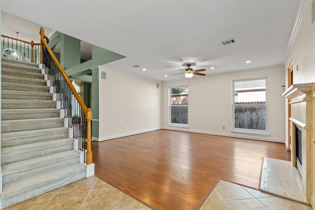 unfurnished living room featuring ceiling fan, a fireplace, light tile patterned flooring, and crown molding