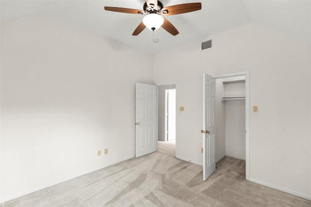 unfurnished bedroom featuring ceiling fan, vaulted ceiling, light colored carpet, and a closet