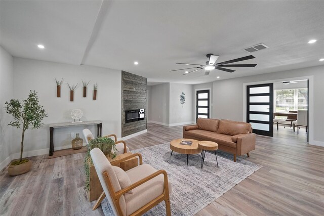 living room featuring a fireplace, french doors, light wood-type flooring, and ceiling fan