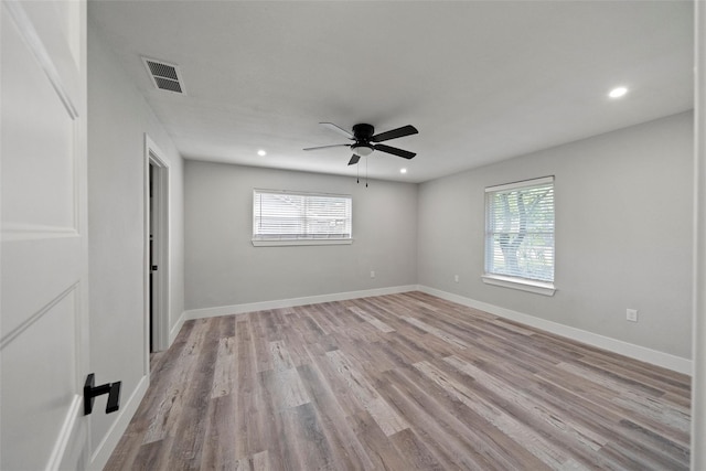 spare room with ceiling fan, a wealth of natural light, and light wood-type flooring