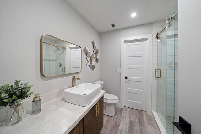 bathroom with vanity, hardwood / wood-style flooring, toilet, and walk in shower