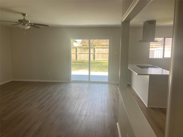 unfurnished living room with plenty of natural light, ceiling fan, and dark wood-type flooring