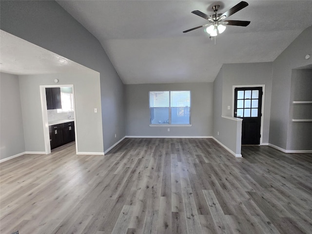 unfurnished living room featuring light wood-type flooring, vaulted ceiling, and ceiling fan