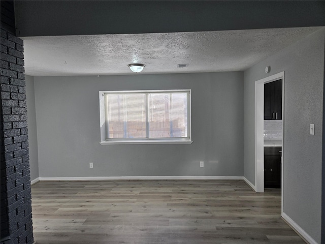 spare room with a textured ceiling and hardwood / wood-style flooring