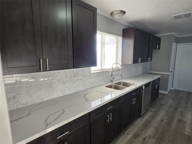 kitchen featuring light stone counters, stainless steel dishwasher, a textured ceiling, sink, and light hardwood / wood-style floors