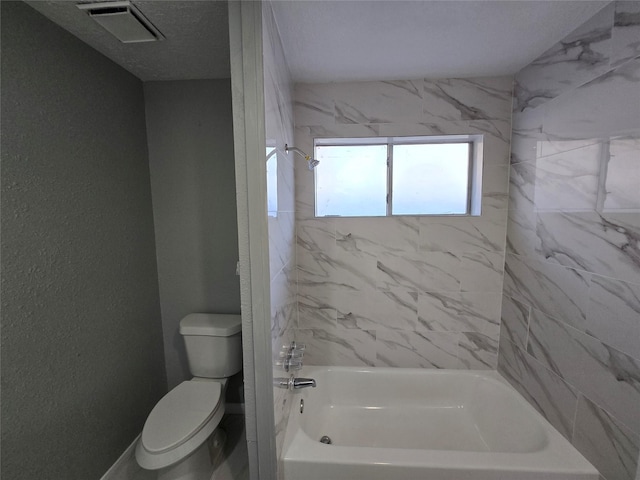 bathroom with toilet and tiled shower / bath