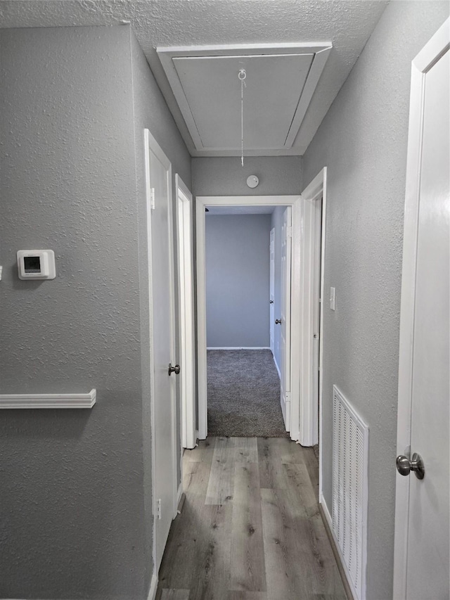 hall with light wood-type flooring and a textured ceiling