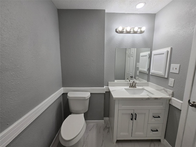 bathroom featuring vanity, toilet, and a textured ceiling