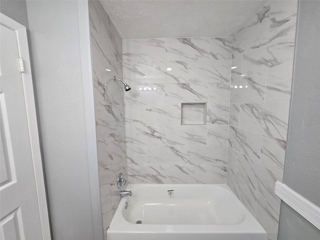 bathroom featuring tiled shower / bath combo and a textured ceiling