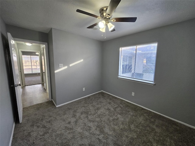 unfurnished room featuring a textured ceiling, dark carpet, and ceiling fan