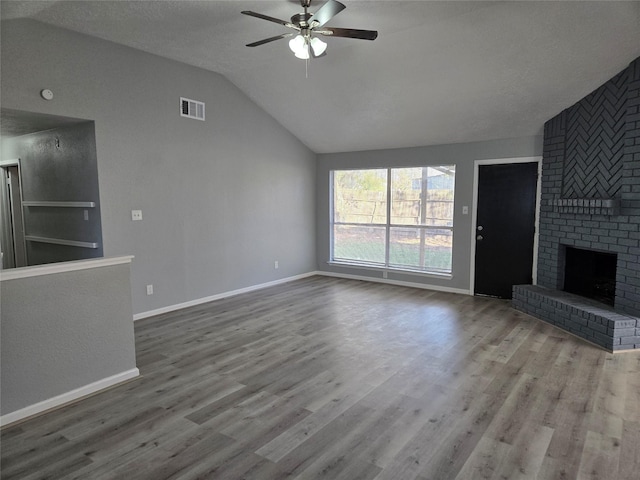 unfurnished living room featuring ceiling fan, wood-type flooring, lofted ceiling, and a brick fireplace