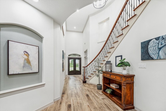 hall featuring french doors, a high ceiling, and light hardwood / wood-style flooring