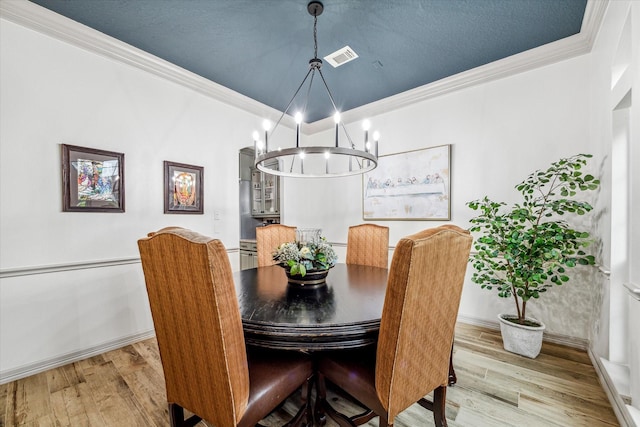 dining area featuring an inviting chandelier, crown molding, and light hardwood / wood-style flooring