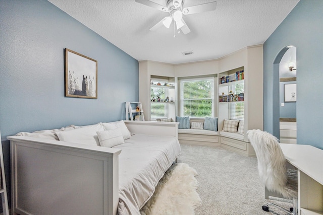 bedroom with ceiling fan, carpet floors, and a textured ceiling