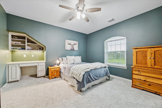 carpeted bedroom featuring ceiling fan and a textured ceiling