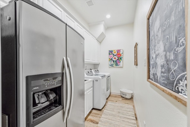 laundry room with washer and dryer, light wood-type flooring, and cabinets