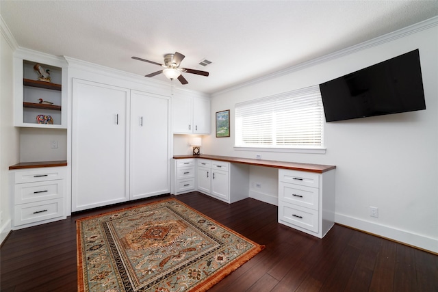 home office featuring ceiling fan, dark hardwood / wood-style flooring, crown molding, and built in desk