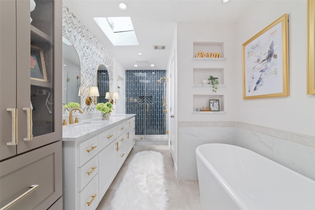 bathroom featuring tile patterned floors, vanity, a skylight, tile walls, and separate shower and tub