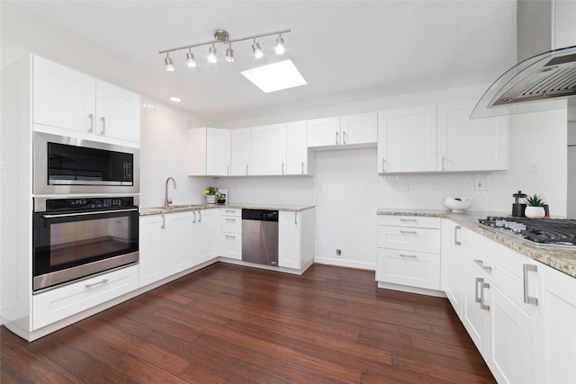 kitchen with white cabinets, light stone countertops, wall chimney range hood, and stainless steel appliances