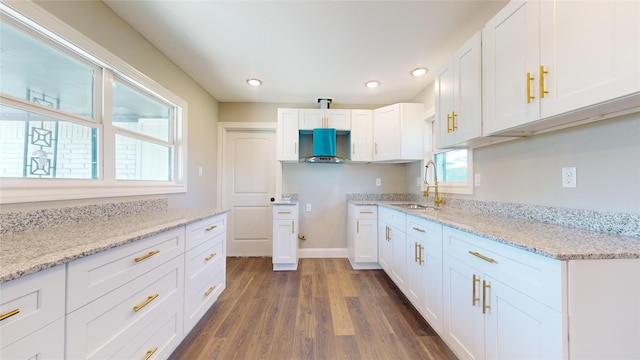 kitchen with light stone counters, a healthy amount of sunlight, dark wood-type flooring, sink, and white cabinets