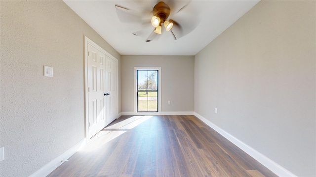 empty room with ceiling fan and dark wood-type flooring